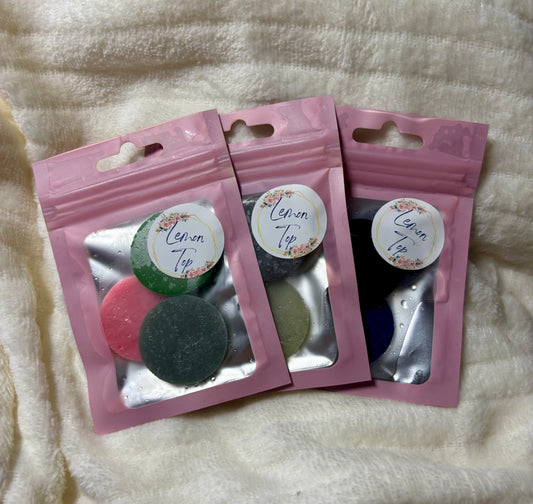 Three pink packages with colorful items on a textured white surface